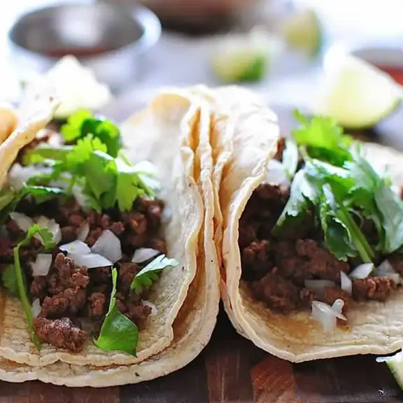Street tacos with seasoned beef, diced onion and fresh cilantro on soft corn tortillas