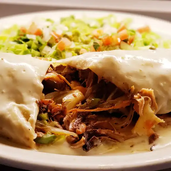 Soft taco filled with slow-cooked shredded meat served on a plate