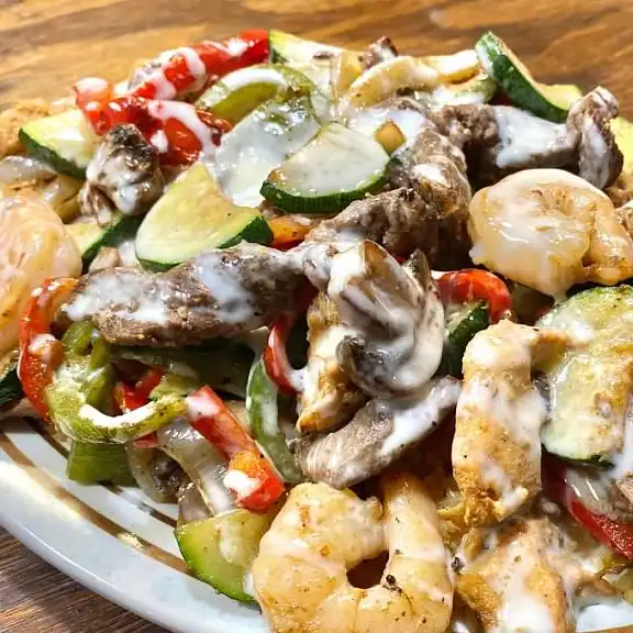 Steak and shrimp sauteed with mushrooms, peppers and zucchini in creamy sauce